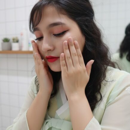 Woman applying skincare on face during Korean glass skin night routine