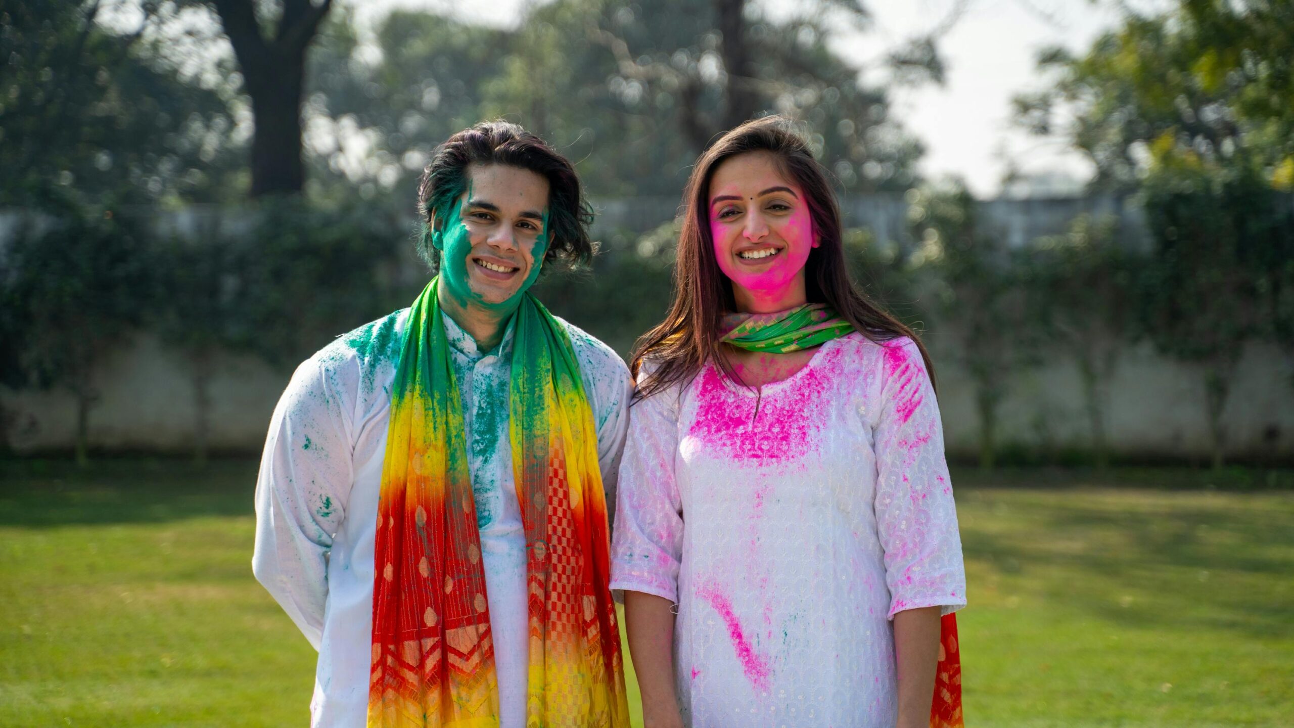 A happy couple celebrating the Holi festival with colorful powder outdoors.