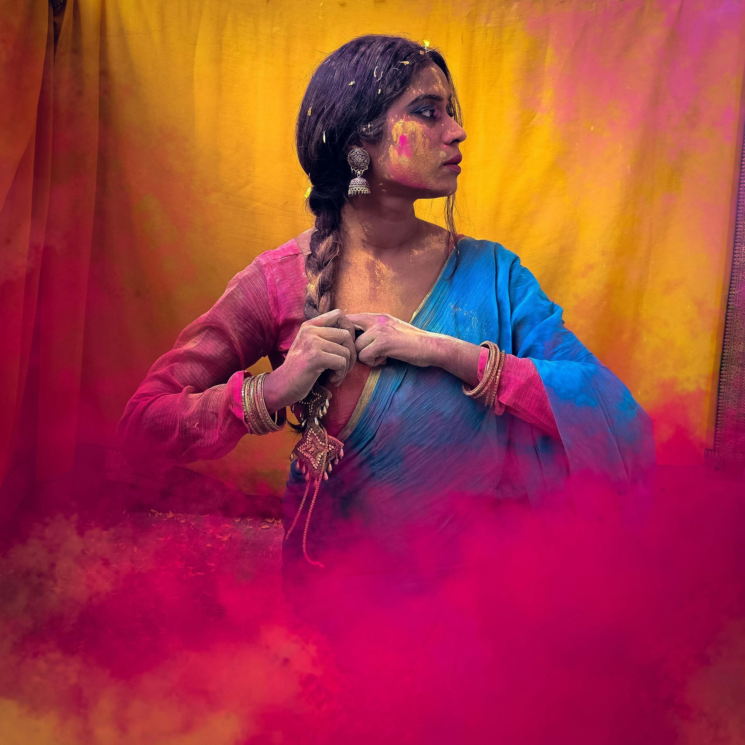 Woman enjoying Holi festival with vivid powder colors on sari and face.